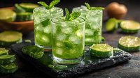Fresh cucumber mint cocktails with ice cubes and sliced ingredients on dark stone board, refreshing summer drinks for restaurant menu and bars.