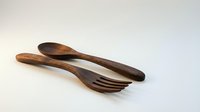 Handcrafted wooden spoon and fork set made from dark wood, eco-friendly kitchen utensils for cooking and serving on isolated white background.