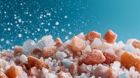 Pink Himalayan and sea salt crystals on turquoise background with falling snow effect, macro food photography for culinary and wellness concepts.