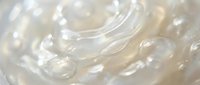 Clear transparent gel texture with smooth flowing waves and glossy surface creating abstract liquid pattern for skincare and cosmetic product backgrounds.