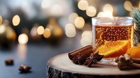 Hot winter drink with orange slice and spices on wooden surface against blurred festive lights background, cozy seasonal beverage for holiday celebration.