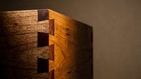 Close-up of wooden dovetail joint showing craftsmanship and precision in furniture making with warm lighting and natural wood grain texture.