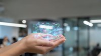 Hand holding futuristic holographic globe with digital network connections in modern office environment for technology presentations.