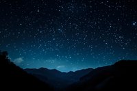 Starry night sky over silhouette mountain range, deep blue gradient with thousands of bright stars creating peaceful cosmic landscape.