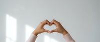 Hands forming a heart shape against a light background, symbolizing love, care, and connection for health and charity concepts.