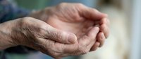 Elderly hands cupped together in gentle gesture showing aged skin texture and wrinkles, representing care, prayer, hope, and senior life experiences.