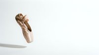 Pink satin ballet pointe shoes with ribbons floating on white background. Dance footwear for classical ballet performance and training isolated.