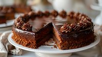 Decadent chocolate layer cake with rich ganache frosting and decorative piped swirls on white plate, cut to show moist texture and dark filling. Perfect for dessert menus.