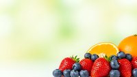 Fresh mixed berries and orange slices on soft blurred background for healthy eating, nutrition concepts, smoothie recipes and organic food designs.