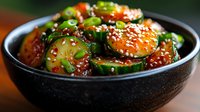 Fresh cucumber kimchi salad garnished with sesame seeds and green onions in black ceramic bowl, vibrant Korean appetizer with sweet and spicy dressing.