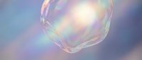 Iridescent soap bubble floating against dreamy purple sky with rainbow reflections and soft light creating magical atmosphere for fantasy designs.