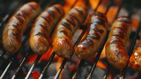 Grilled sausages cooking on barbecue grill with glowing hot coals beneath, perfect for food marketing, restaurant menus, and summer cookout promotions.