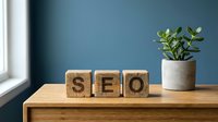 Wooden blocks spelling SEO on a desk with a green plant and blue wall, representing search engine optimization for digital marketing.