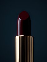 Luxury dark red lipstick with golden tube against moody background for premium cosmetics and beauty product photography.