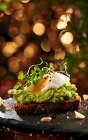 Gourmet avocado toast with poached egg and microgreens on dark bread against festive bokeh background for food blog or restaurant menu.
