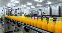 Industrial orange juice production line with bottles on conveyor belt in modern food processing facility with workers in safety uniforms and stainless steel equipment.