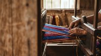 Traditional weaving loom with colorful threads in rustic workshop setting, showcasing handcraft textile production and artisan skills for cultural heritage projects.