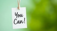 White paper tag with You Can motivational message hanging on rope against soft green blurred background for inspiration and encouragement concepts.