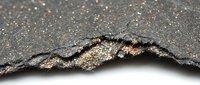 Torn edge of glittery metallic paper with gold and silver sparkle texture against white background for design projects and creative overlays.