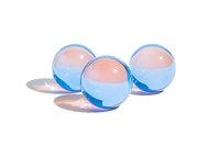 Translucent blue glass marbles with pink centers casting soft shadows on white surface, isolated composition for creative design and decoration purposes.