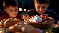 Young boys enjoying loaded nachos with melted cheese, sour cream and toppings in woven basket during evening gathering with bokeh lights and fresh bread rolls.