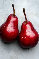 Fresh red pears with water droplets on marble background, showcasing vibrant color and natural texture for food photography.