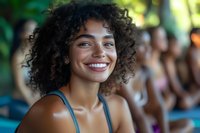 Happy young African American woman with curly hair smiling at camera during outdoor summer event with blurred people in background for lifestyle content.