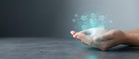Caucasian male hand holding glowing digital network nodes and blockchain technology symbols on gray surface for business innovation and data connectivity concepts.
