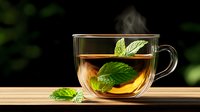 Glass cup of steaming hot mint tea with fresh green leaves on wooden surface against dark background, aromatic beverage photography for wellness and relaxation.