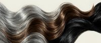 Flowing wavy hair strands in natural brown, black and silver tones creating elegant texture pattern for beauty and haircare concepts.