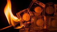 Fire and ice cubes creating dramatic contrast with orange flames melting frozen water blocks against dark background for hot cold temperature concepts.