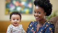 Joyful African American mother and baby sharing tender moment at home, wearing floral patterns. Natural lighting highlights genuine emotions and family bonding.
