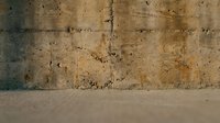 Weathered concrete wall with aged tan and brown surface showing cracks, stains, and texture. Suitable for backgrounds, industrial design, grunge effects, and urban projects.