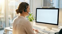 Professional businesswoman with headset working at computer in modern office environment for customer service and remote work applications.