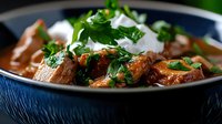 Beef stew with tender meat chunks, rich brown broth, fresh parsley garnish, and creamy sour cream served in dark bowl for comfort food dining and culinary content.