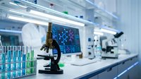 Modern laboratory with microscope and test tubes for scientific research and medical analysis in sterile environment with digital displays.