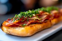 Fresh submarine sandwich with layers of cured meat, melted cheese and chopped herbs on crusty baked bread, close-up view with selective focus on garnish.