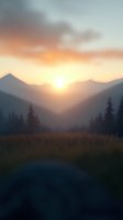 Misty mountain landscape at sunrise with golden sky, silhouetted peaks, and tall grass in foreground creating atmospheric outdoor scene for nature backgrounds.