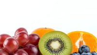Fresh colorful fruit mix with red grapes, kiwi slice, orange segments and blueberries on white background for healthy eating and nutrition concepts.