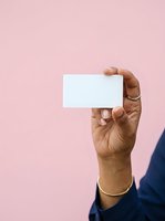 Hand holding blank white business card against pink background, ideal for branding and corporate identity mockups.