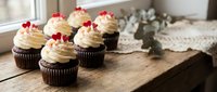 Chocolate cupcakes with vanilla frosting and red berries on rustic wooden table. Holiday dessert display for bakery menu and celebration treats.