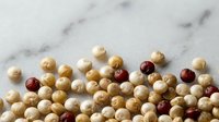Assorted round wooden beads in natural tan and deep burgundy tones arranged on marble surface for craft projects, jewelry making, and decorative applications.