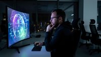 Focused businessman analyzing global data visualization on computer screen in modern office environment during evening work session.