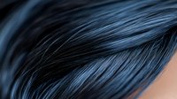 Close-up macro shot of dark blue hair strands with soft focus and smooth texture, showing detailed structure of dyed or colored hair against blurred background.