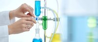 Female scientist hands adjusting laboratory equipment with colorful chemical solutions in modern research facility for pharmaceutical development.