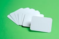 Blank white business cards fanned out on vibrant green background, perfect for branding mockup and corporate identity design presentation. Isolated cards with rounded corners for design showcase.