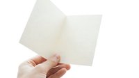 Open blank notebook with lined pages held in hands on white background for writing, journaling, and note-taking projects.
