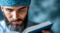 Middle Eastern man with gray beard wearing traditional turquoise headscarf reads book with focused expression against blurred blue background. Spiritual and educational concept.