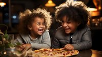 African American mother and young daughter sharing joyful moment while eating pizza at restaurant, genuine laughter and bonding during casual dinner outing.