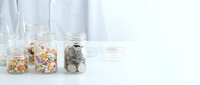 Glass jars filled with colorful pills, capsules and coins on white table representing healthcare costs, medical expenses and pharmaceutical savings.